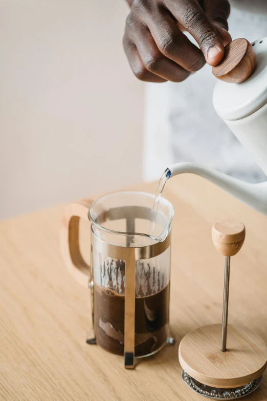 a person pours water from a glass cup to a pitcher