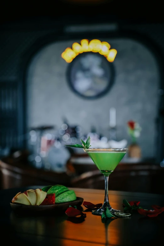 a green cocktail sits on a wooden table