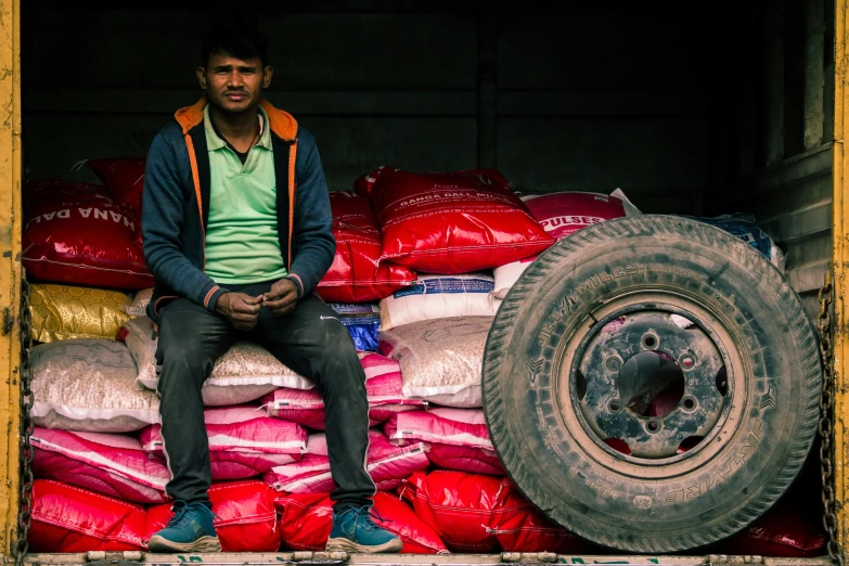 a man sitting on the back of a truck filled with bags