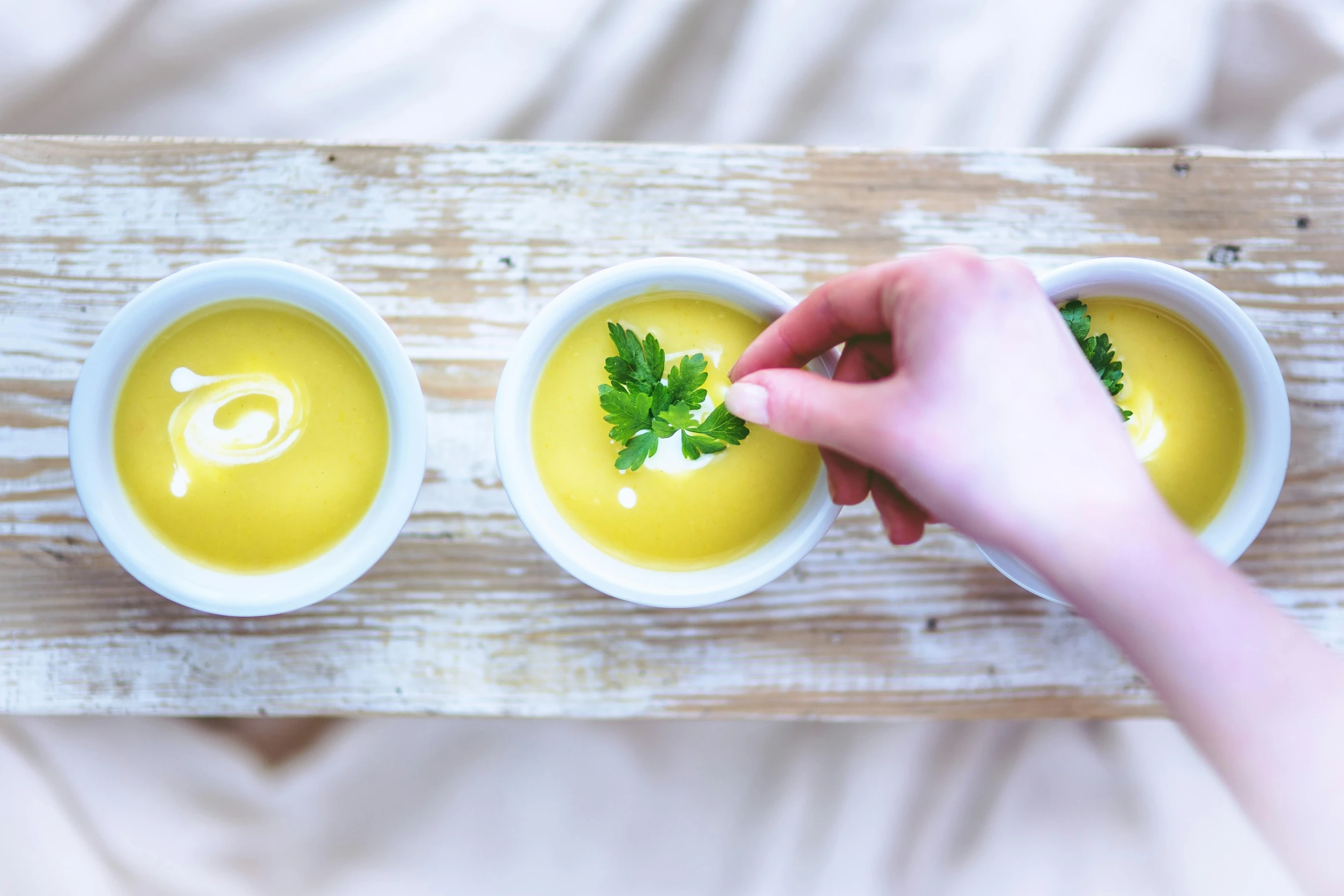 a person holding their finger up to a bowl of soup