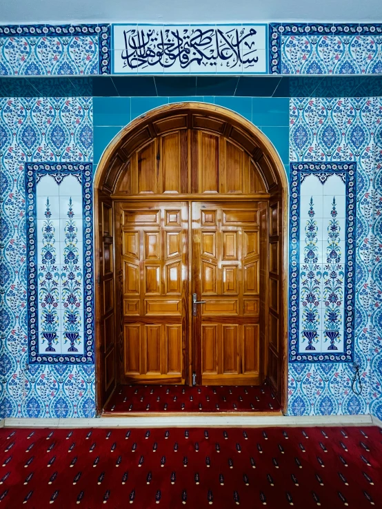 a doorway into a large blue tiled room with wooden doors