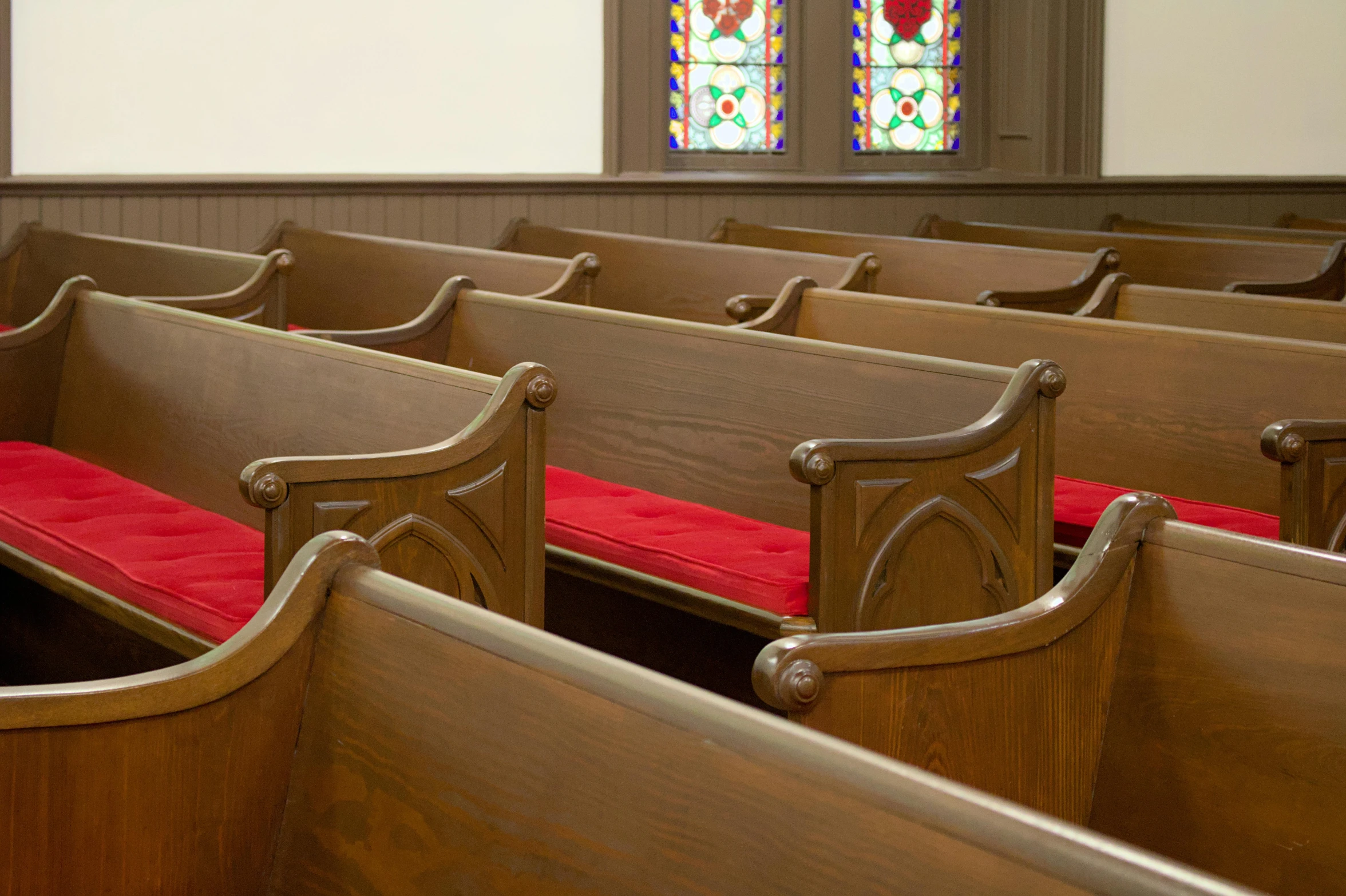 wood pews with red seat covers in an old church