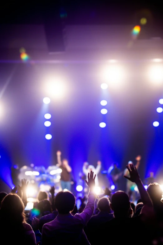 concert lights and spectators watching with their hands in the air