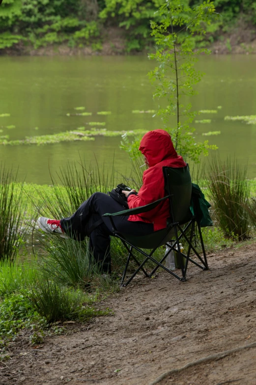 an open lawn chair in a field next to a lake