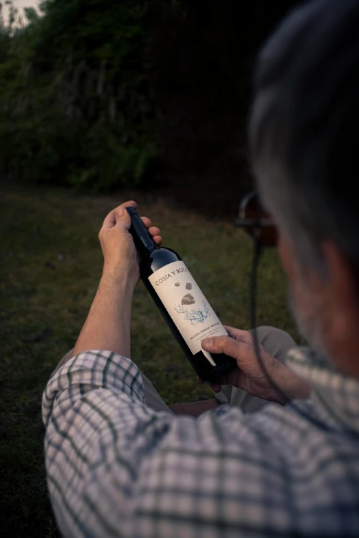 a man is holding a bottle of wine and examining it