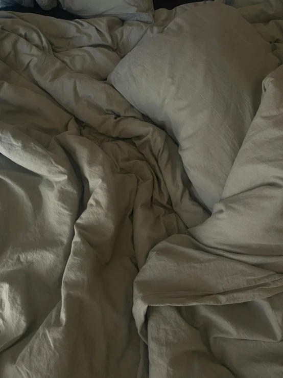 an unmade bed with some soft pillows