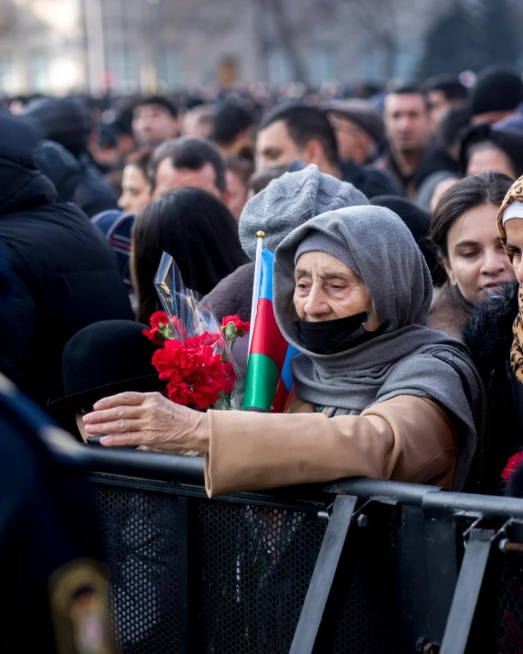 a woman looking over the side of a fence while another woman holds a flowers