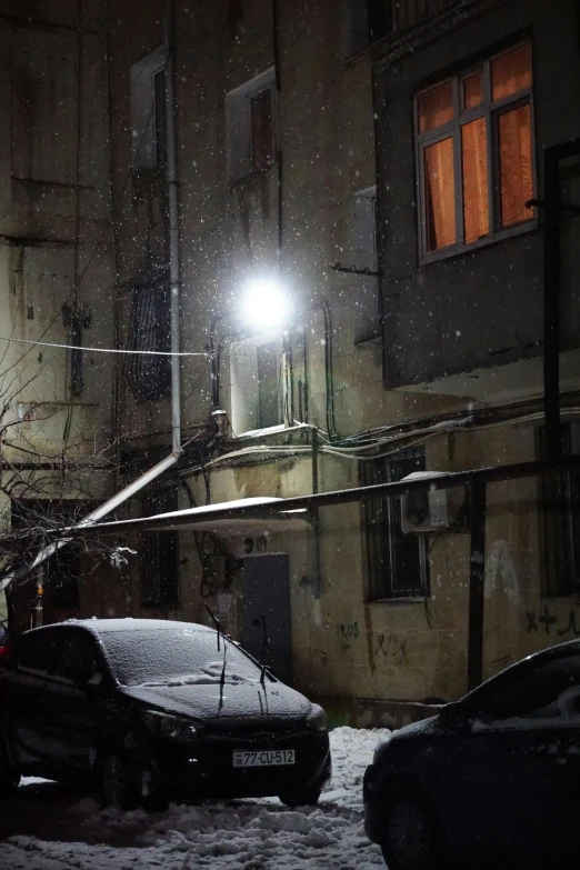 a snowy night with two cars on a city street