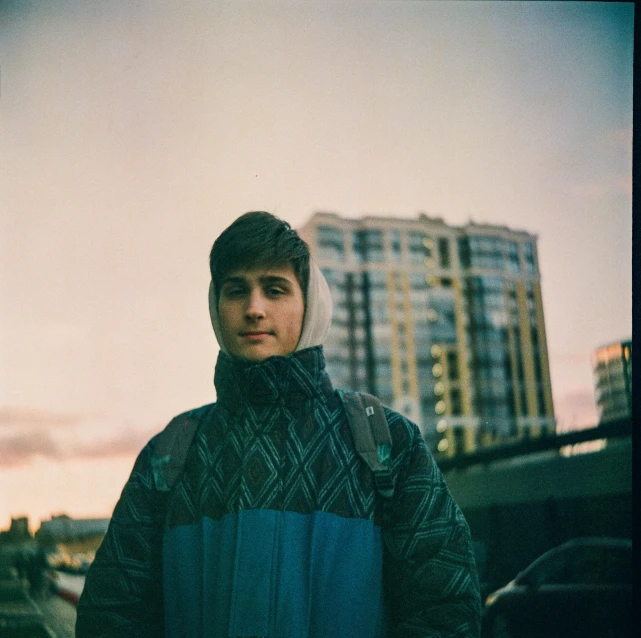 a young man standing in front of some tall buildings