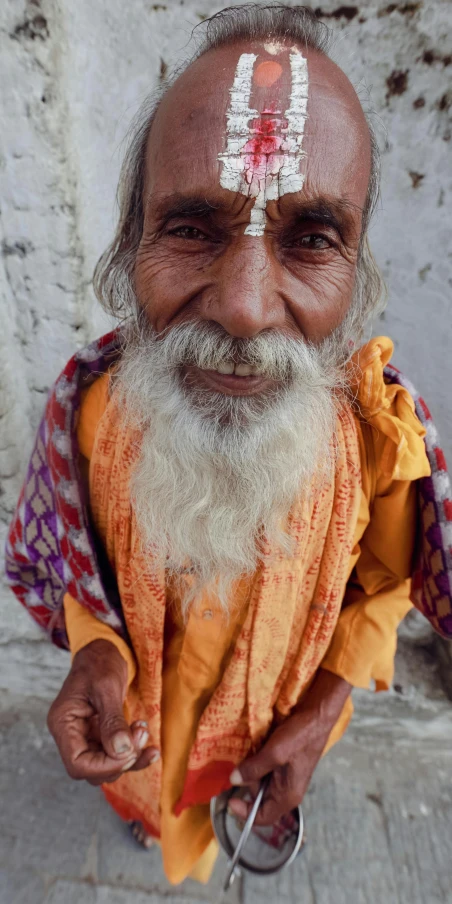 a man with a long white beard and white eyes wearing an orange shawl