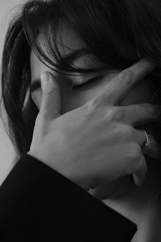 a black and white pograph of a woman holding her hands over her face