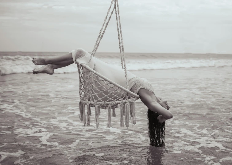 a woman laying on a chair suspended above the ocean water