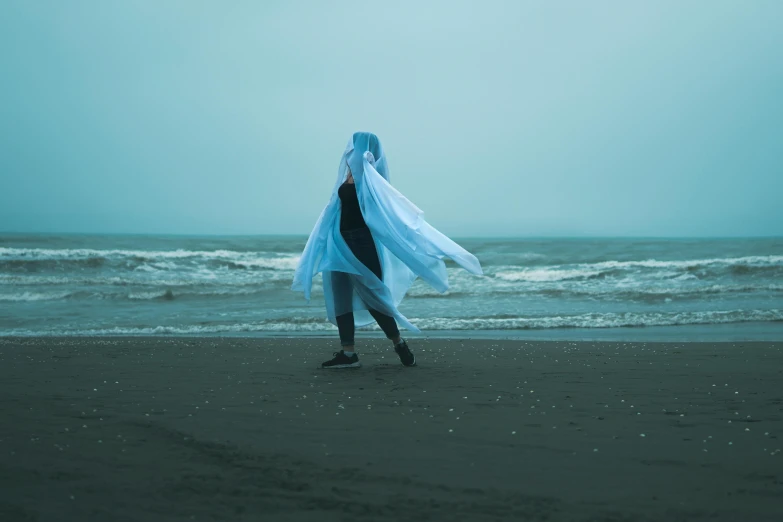 a woman is wearing blue and white near the ocean