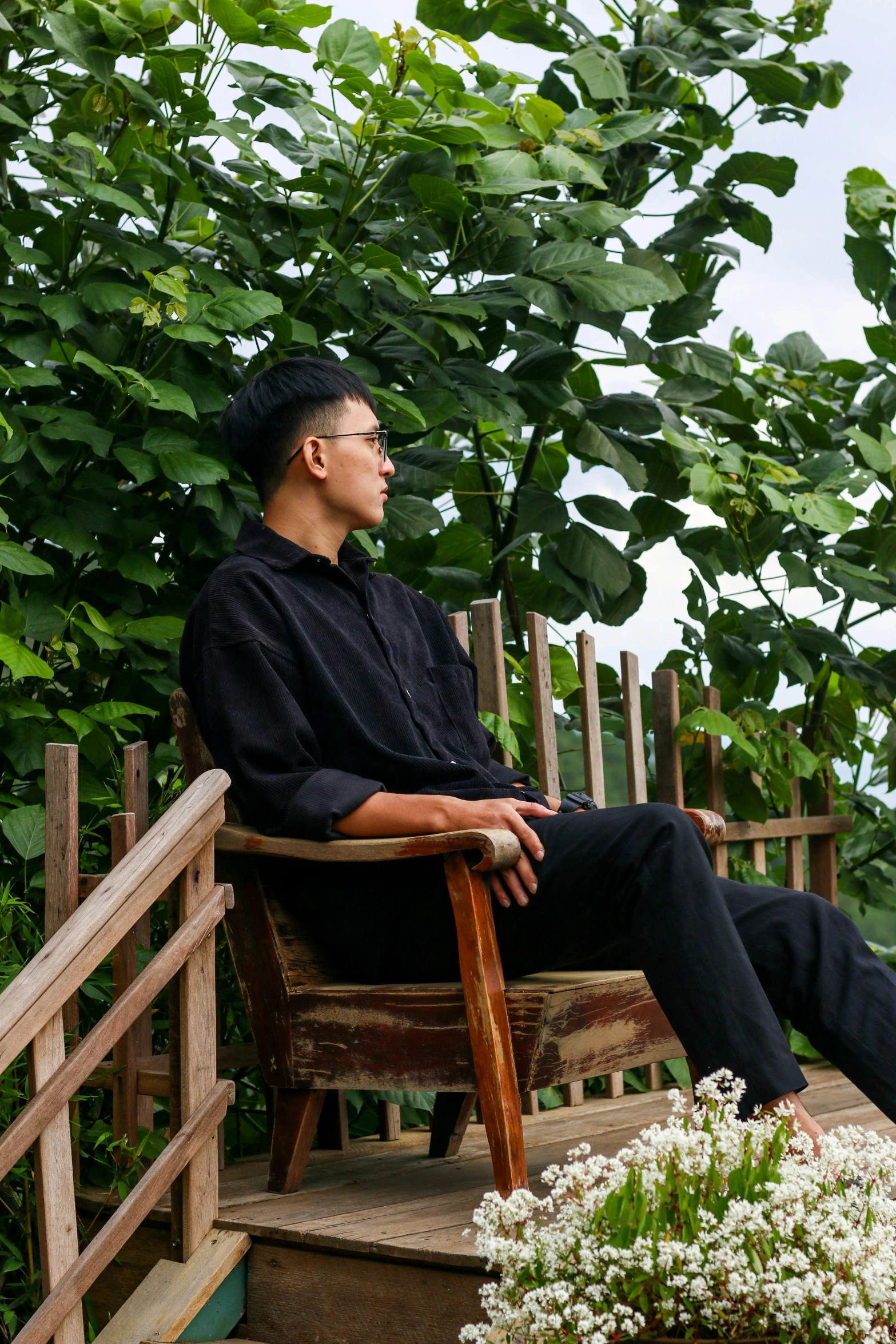 a man sits in a wooden chair, looking up