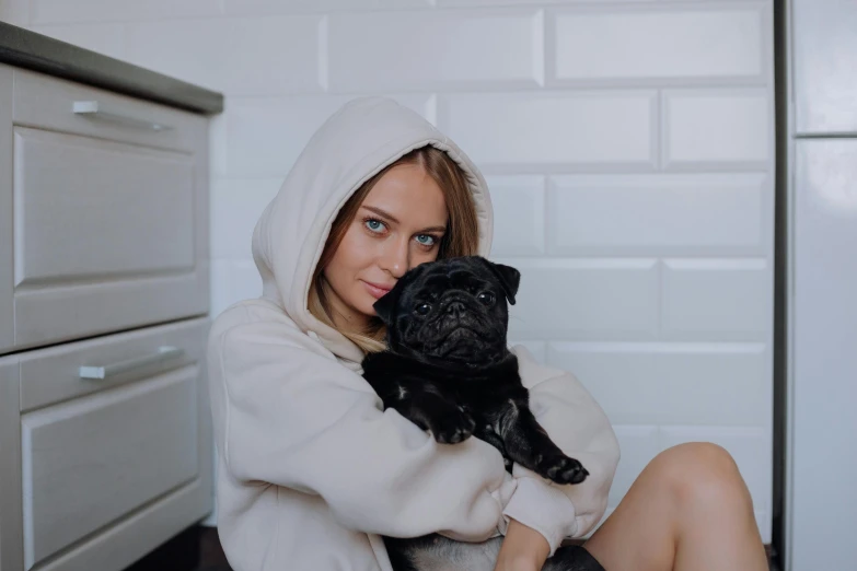 a woman in white sweater holding a black dog