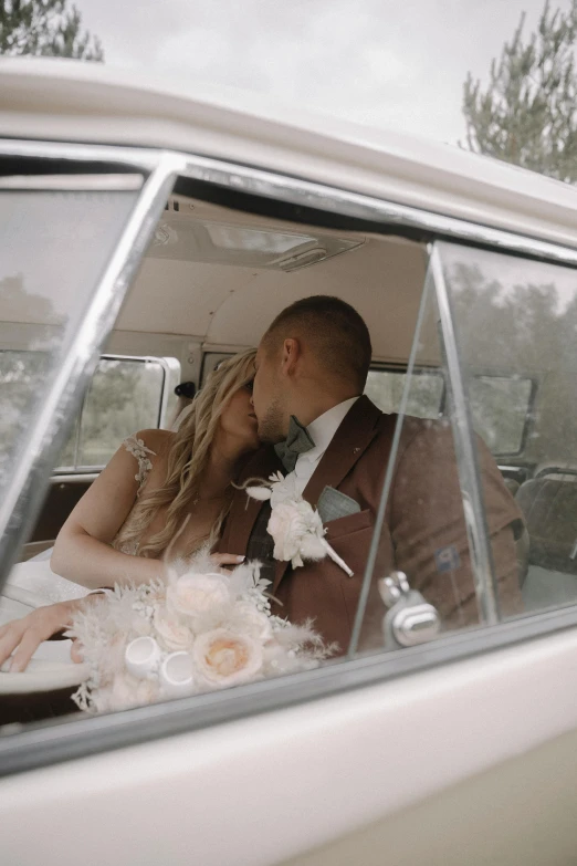 man and woman kissing in a white car, with one holding flowers in her lap