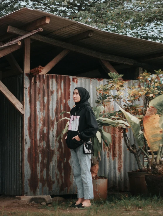 a woman standing in front of a rusted building