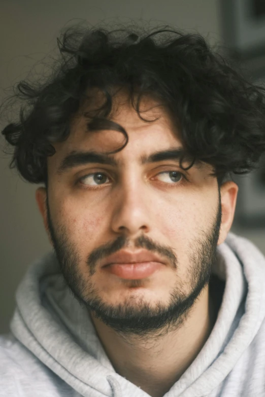 the man is posing with curly hair and has a beard