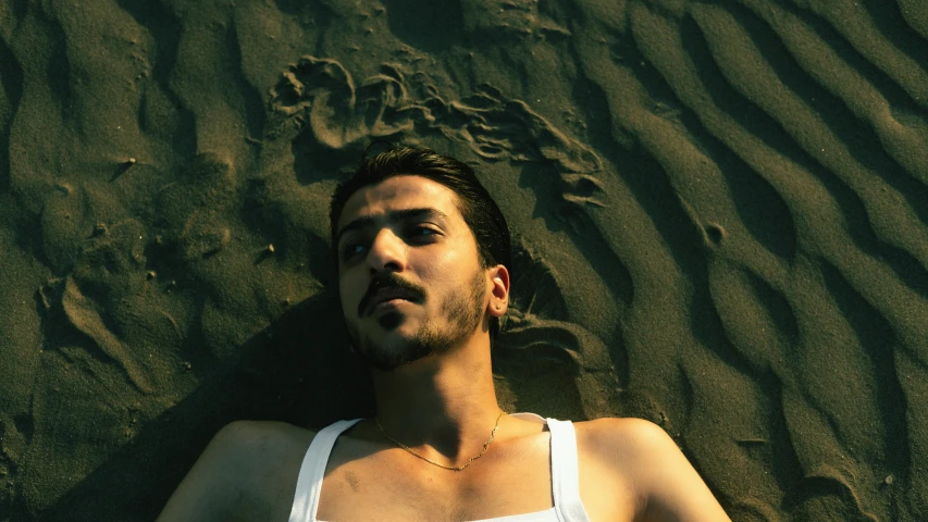 a man laying on the beach with his eyes open