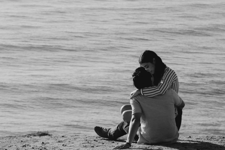 two people are sitting on the beach and talking