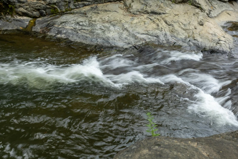 water running into the ocean next to a rock formation