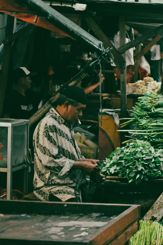a man in a market area chopping green vegetables