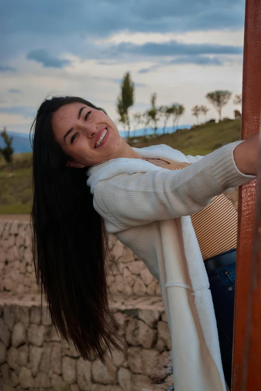 an attractive woman holding onto the pole of a fence