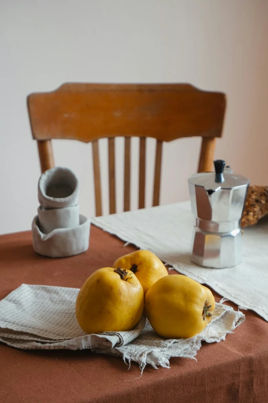 four mangoes on top of a white cloth in front of a wooden table