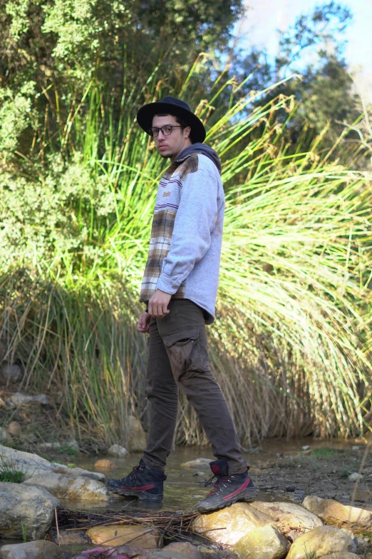 a man standing in the water next to rocks and trees