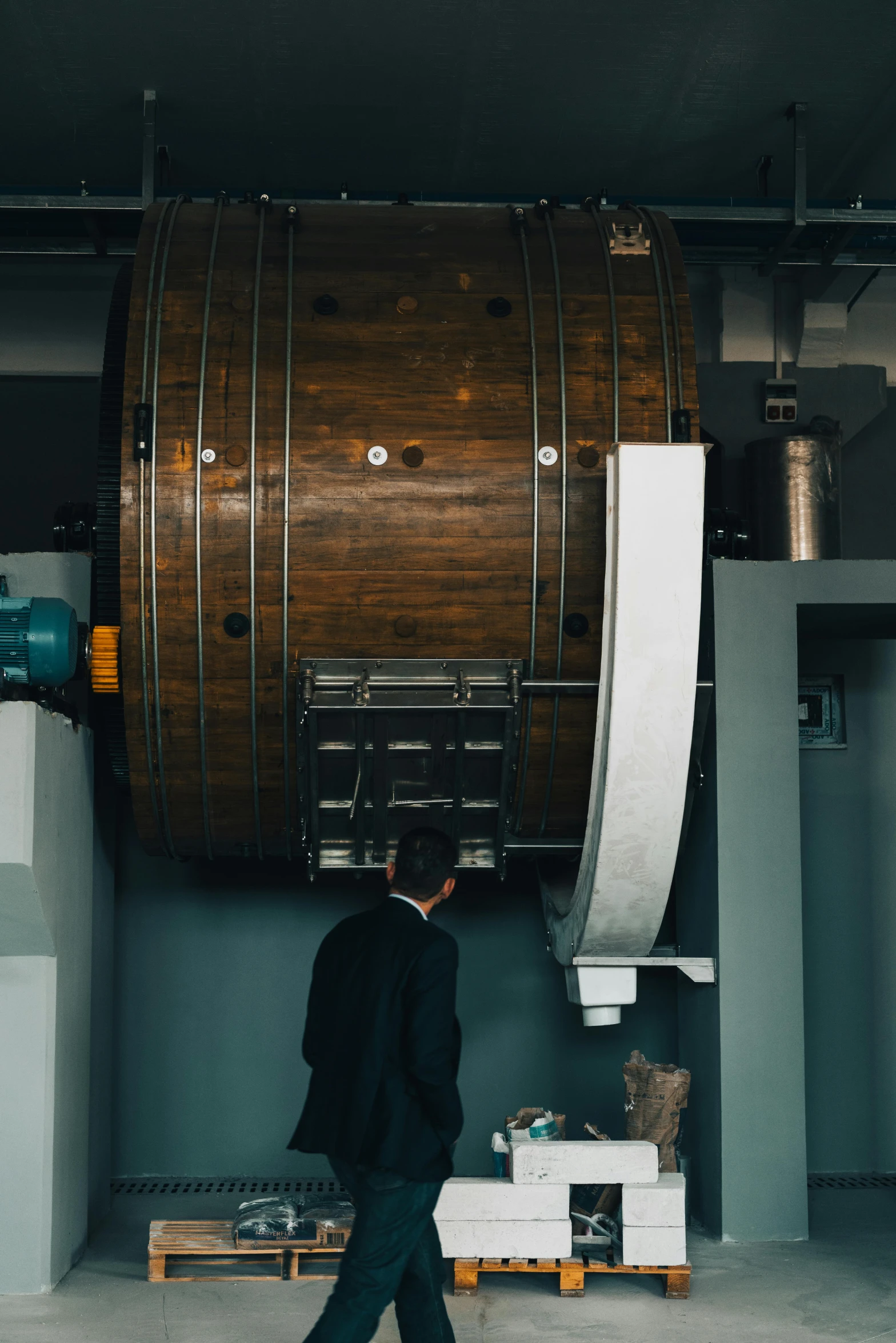 a man in a black suit walks past a huge barrel