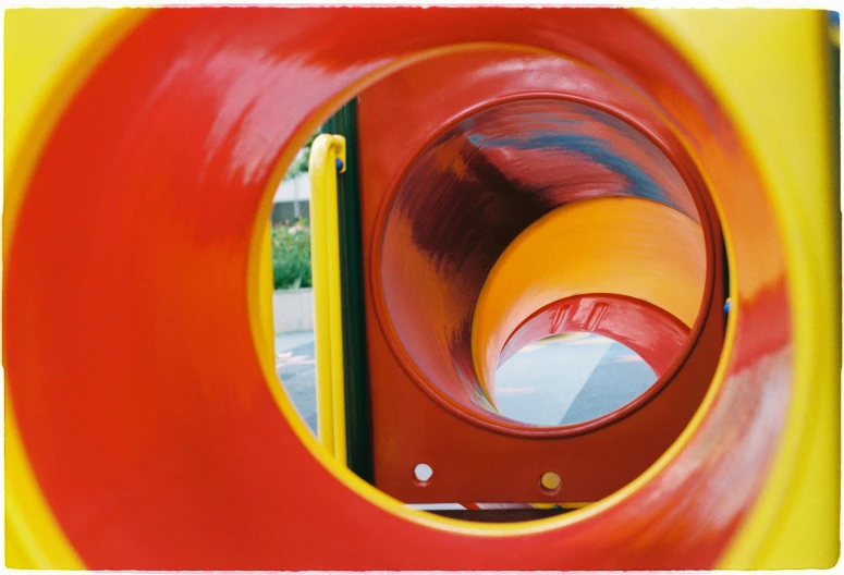 a red and yellow slide sitting in the middle of a park