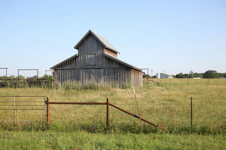 a barn on the side of a farm with a fence in front of it