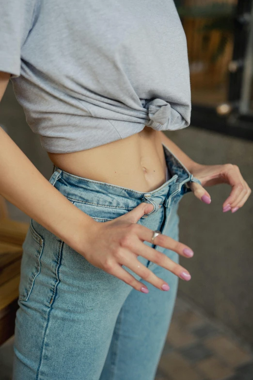 a woman wearing blue jeans has her hand in her pocket