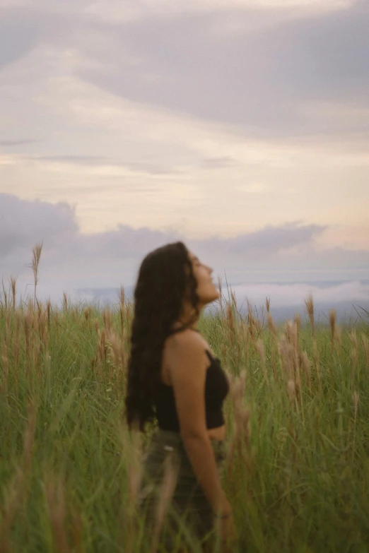 a woman in a black top sitting on top of a lush green field