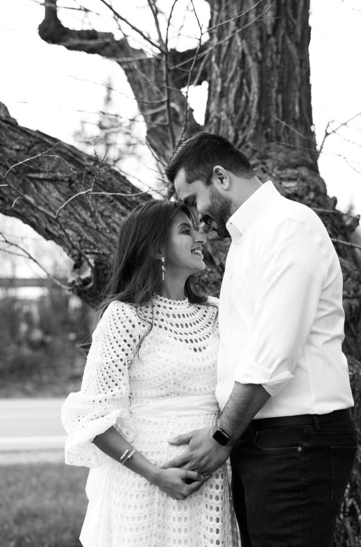 a couple standing next to each other under a tree