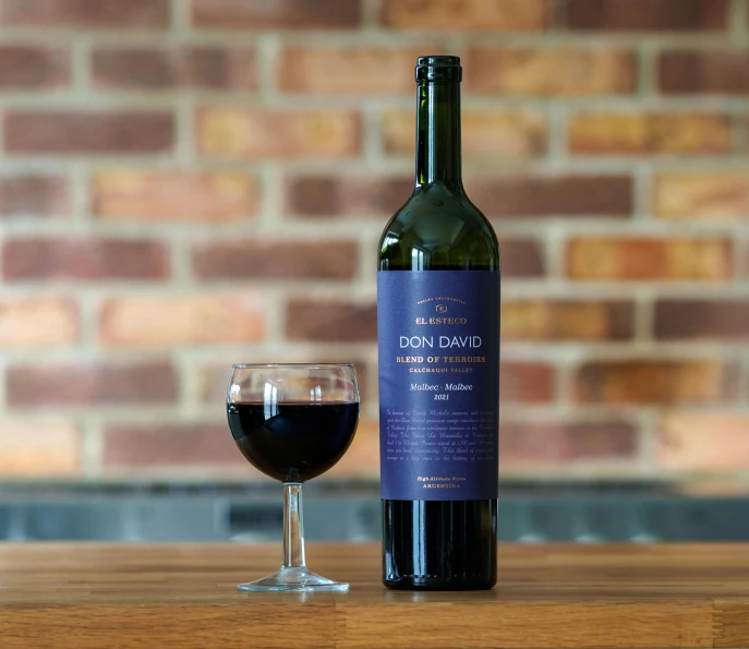 a close up of a bottle of wine on a table with a wine glass