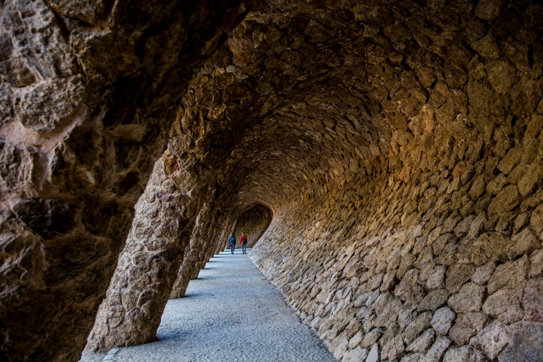 people are walking through a tunnel of stone