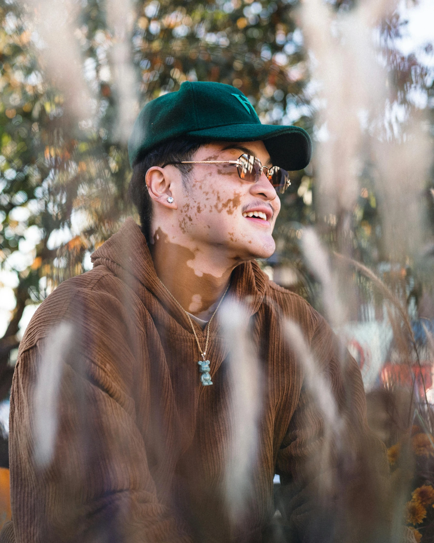 a man wearing sunglasses, a green hat and a brown jacket