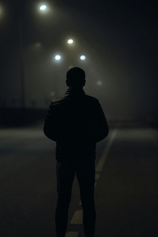 a man standing at night alone in a parking lot