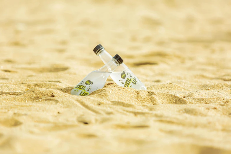 two glasses that are stuck in the sand