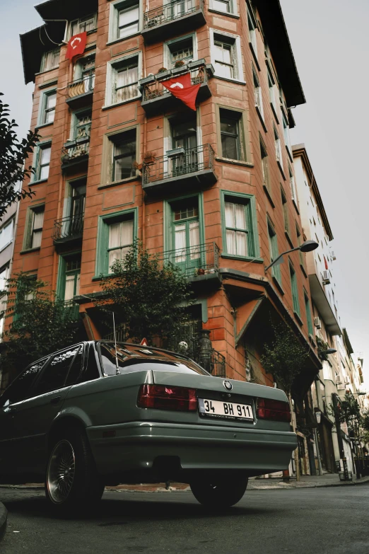 an odd car is parked in front of a very large building