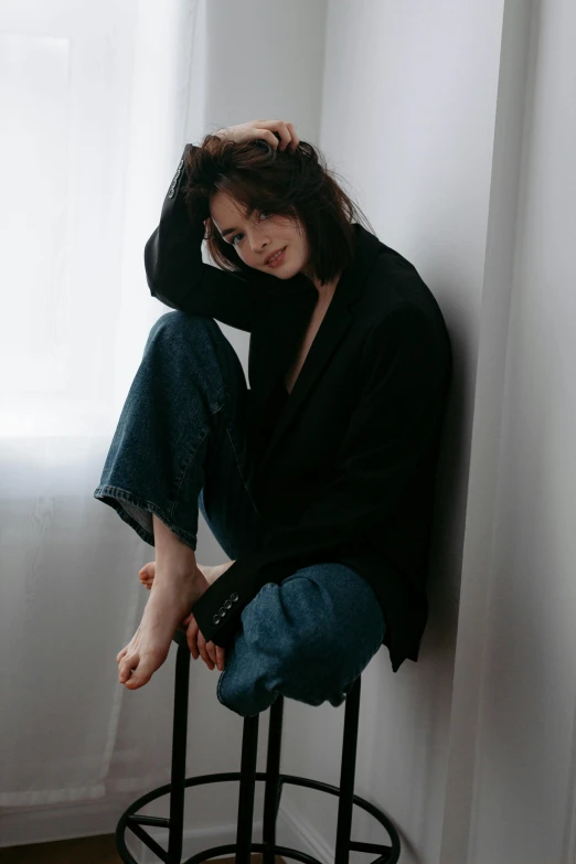 a girl sitting on top of a stool holding her hair