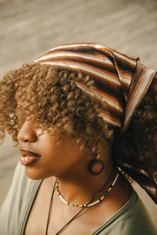 a woman wearing a striped headdress with her hair tied