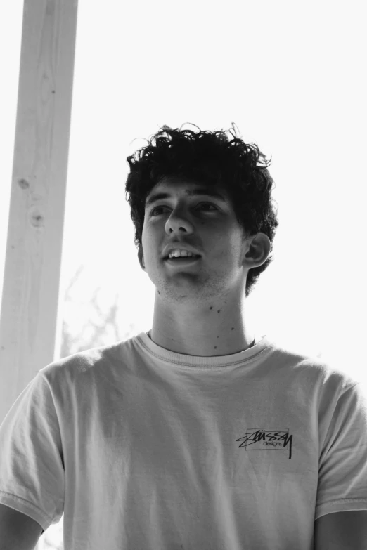 a young man wearing a t shirt standing in a corner