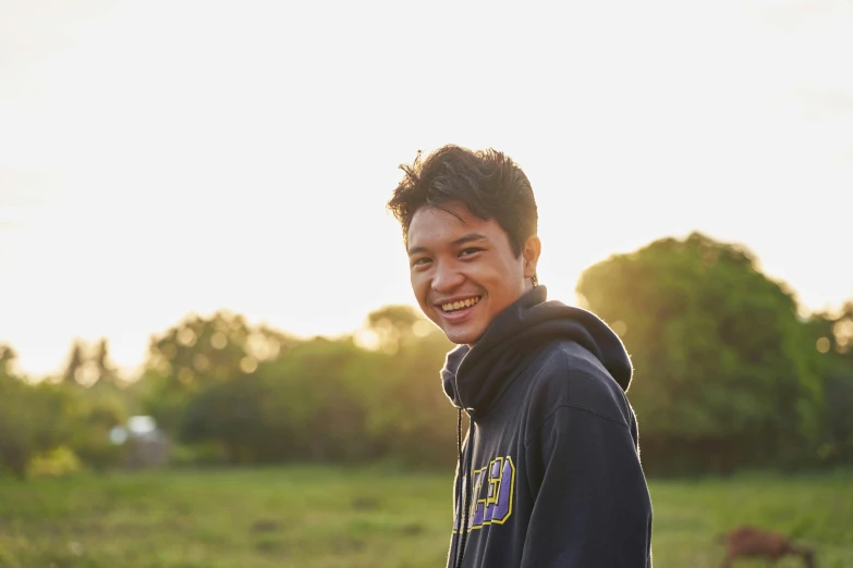 a young man is smiling in a field