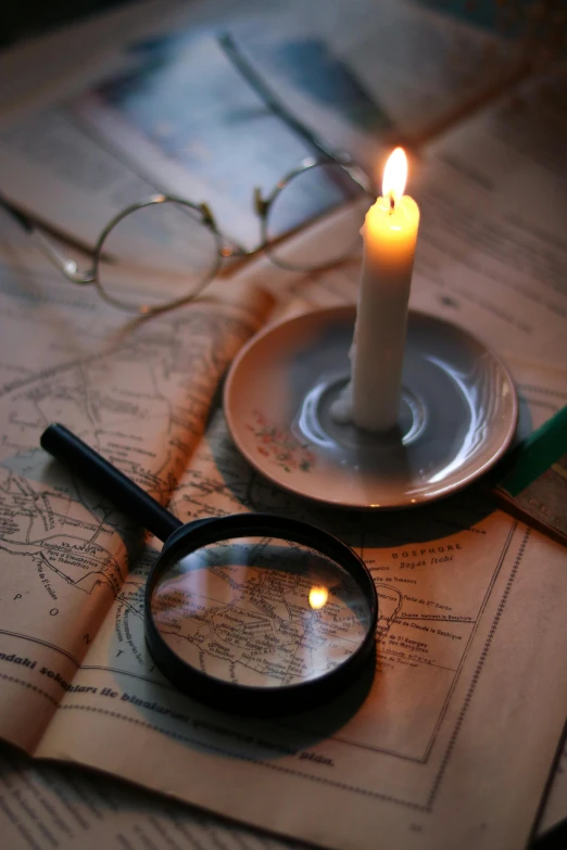 a candle and magnifying glass on a map