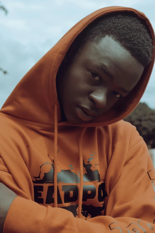 a  in an orange sweatshirt with his arms crossed