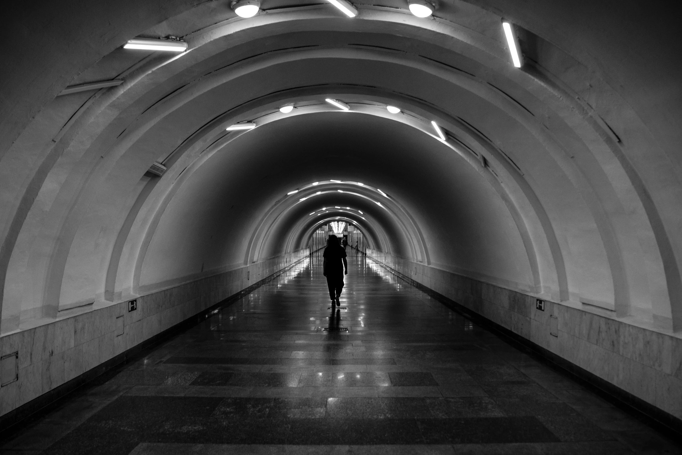 a lone person walks through a dark tunnel