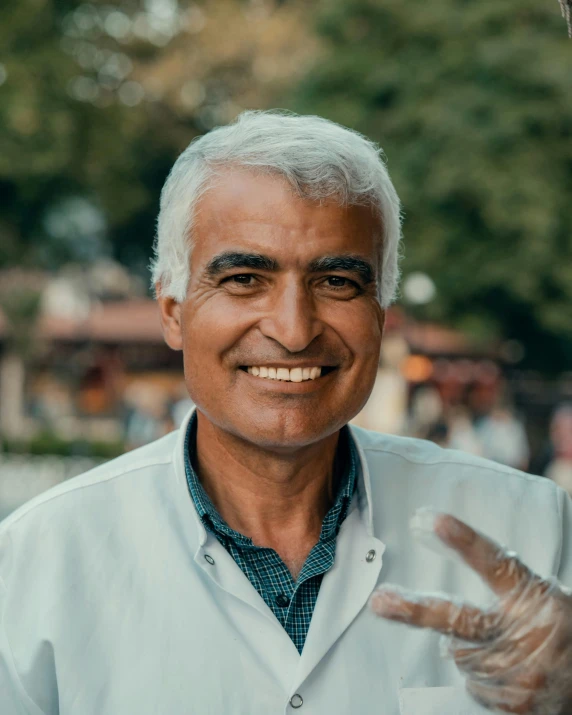 a white - haired male smiling at the camera and waving to someone else
