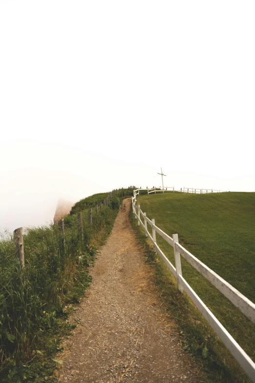 a road and fence near a grassy hill